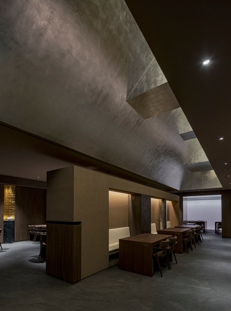 View toward dining booths with angled skylight casting natural light across the textured ceiling surface