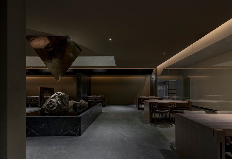 View across the dining area showing the stone installation and polished ceiling planes overhead