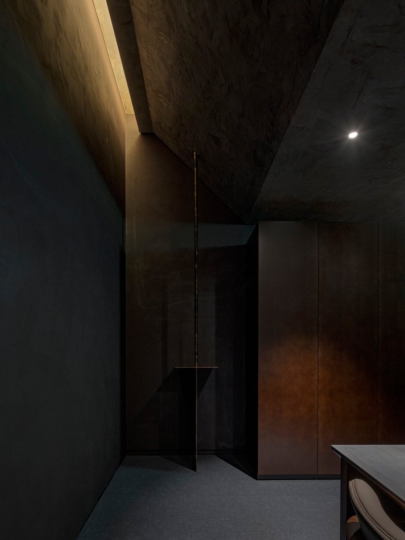 Corridor with exposed concrete ceiling and a narrow illuminated slot along the timber wall
