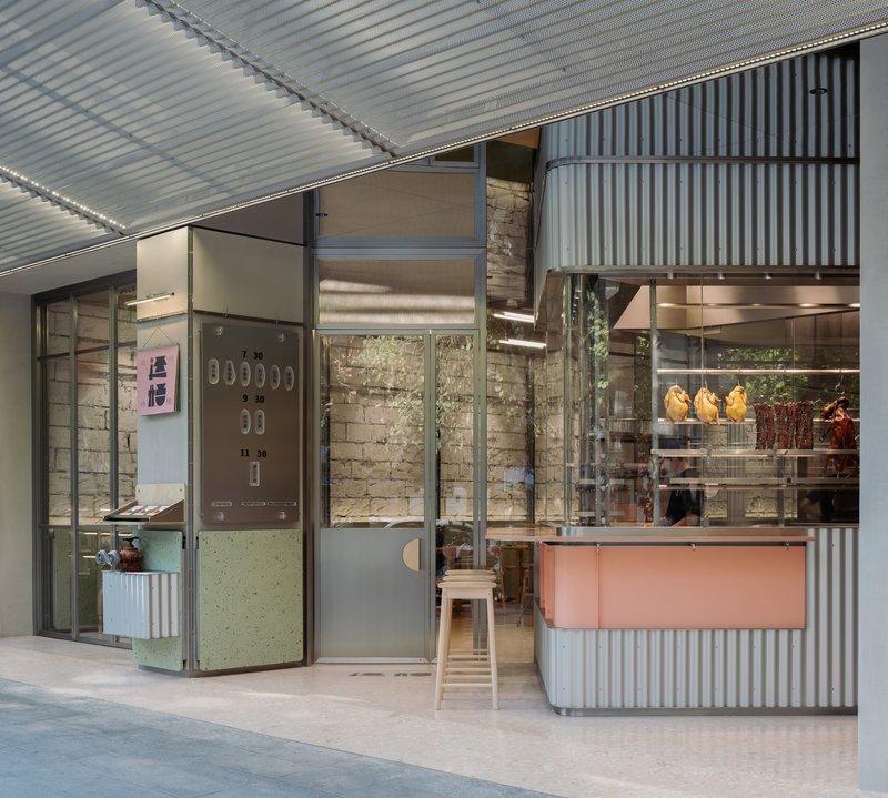 Entrance detail showing pale green folding door, exposed brick wall and corrugated metal cladding in daylight