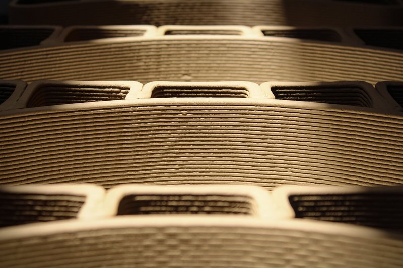 Detail view of layered cardboard or laminated material showing horizontal striations and rectangular cutouts in dramatic lighting