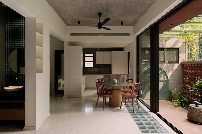 Open-plan dining area with terrazzo flooring opening onto a planted courtyard through sliding glass doors