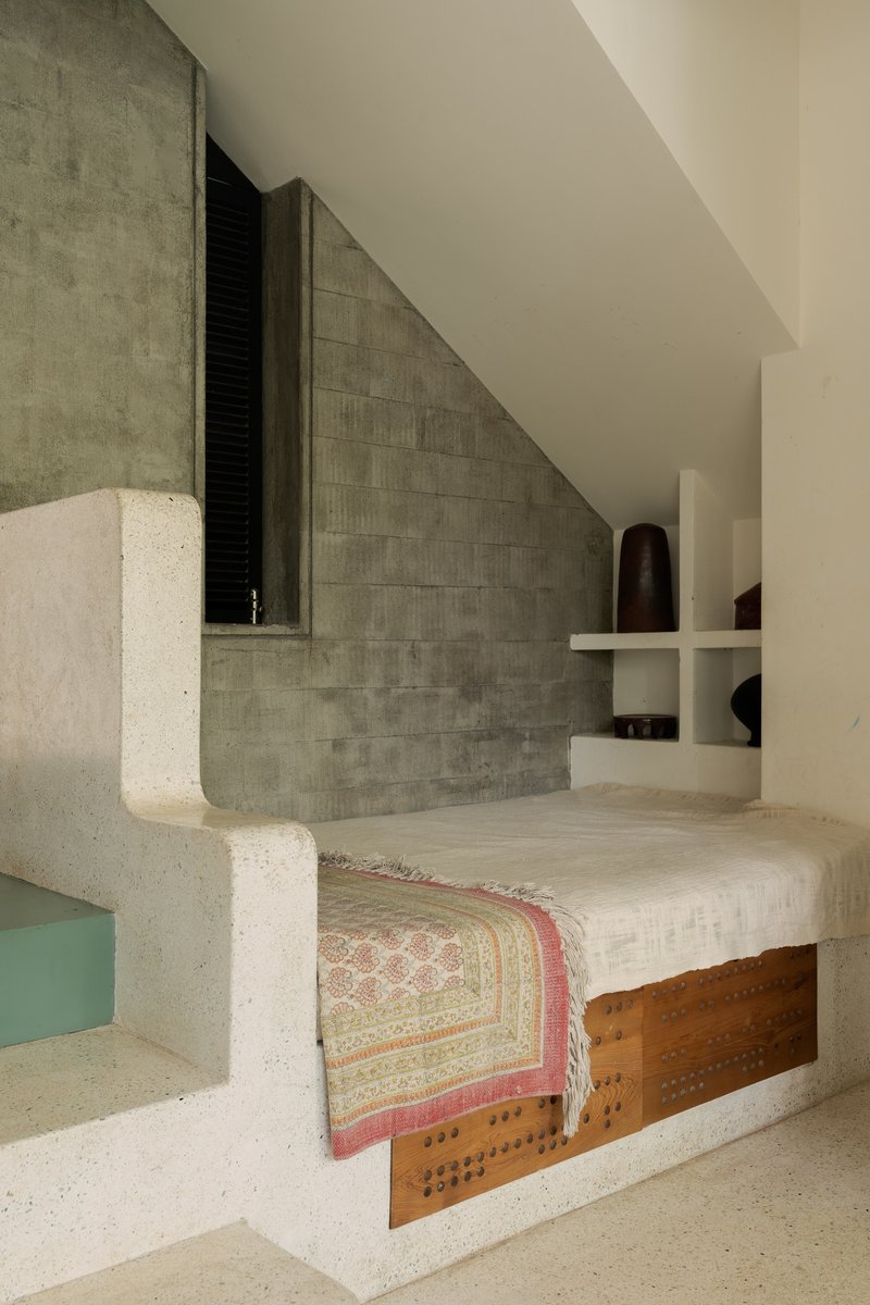 Built-in concrete daybed with timber storage compartment against a grey tile wall