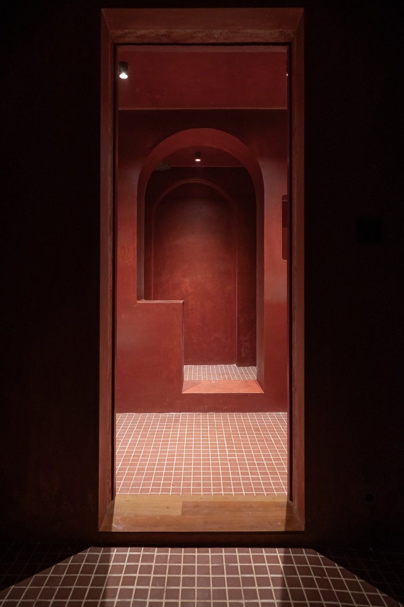 Sequence of arched doorways receding into darkness with tiled threshold and red plastered walls