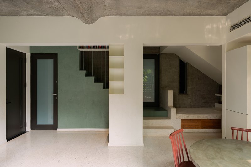Interior view of floating staircase with integrated lighting treads ascending past a green textured wall