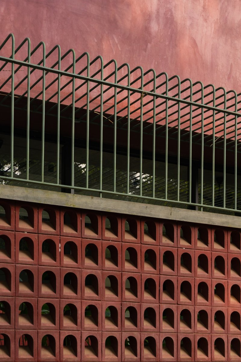 Close-up of the terracotta perforated screen with triangular metal railing above the concrete ledge