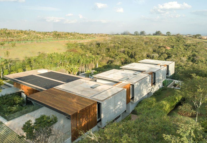 Aerial view of a concrete flat roof with solar panels and timber screens set in farmland