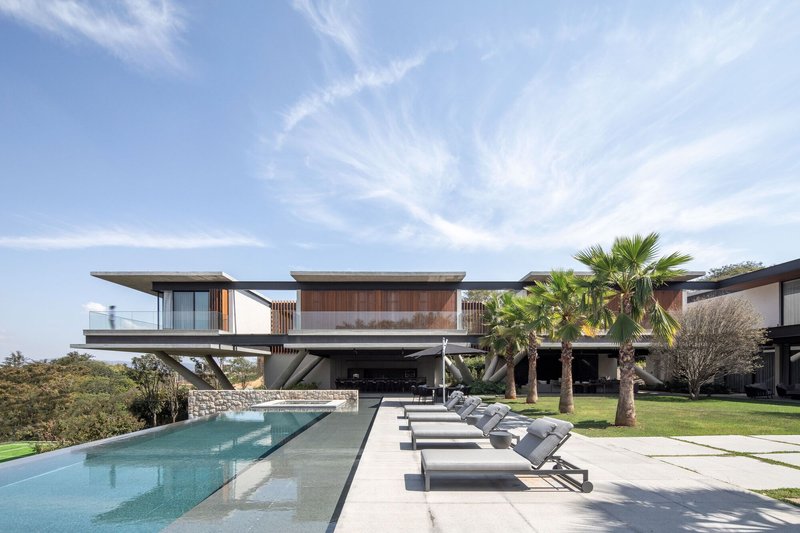 Pool deck with stone loungers facing the elevated structure supported by angled concrete columns