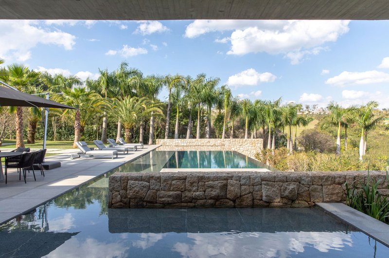 Tiered pool with rough stone retaining wall framed by palms under partly cloudy sky