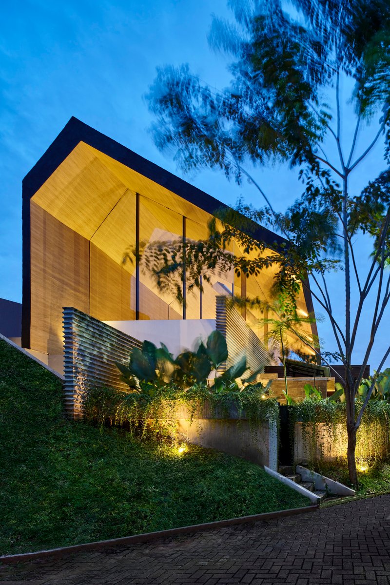Facade showing the cantilevered timber-paneled upper floor above planted terraces at twilight