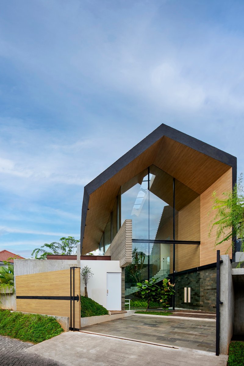 Front facade showing the cantilevered timber-lined volume framing the entrance and sculptural staircase beyond