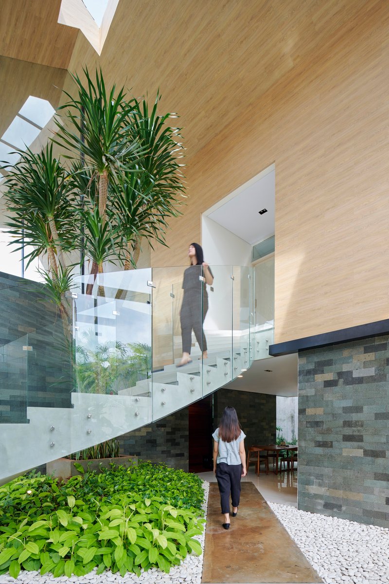 Cantilevered white staircase with glass balustrades and residents in motion near variegated stone walls