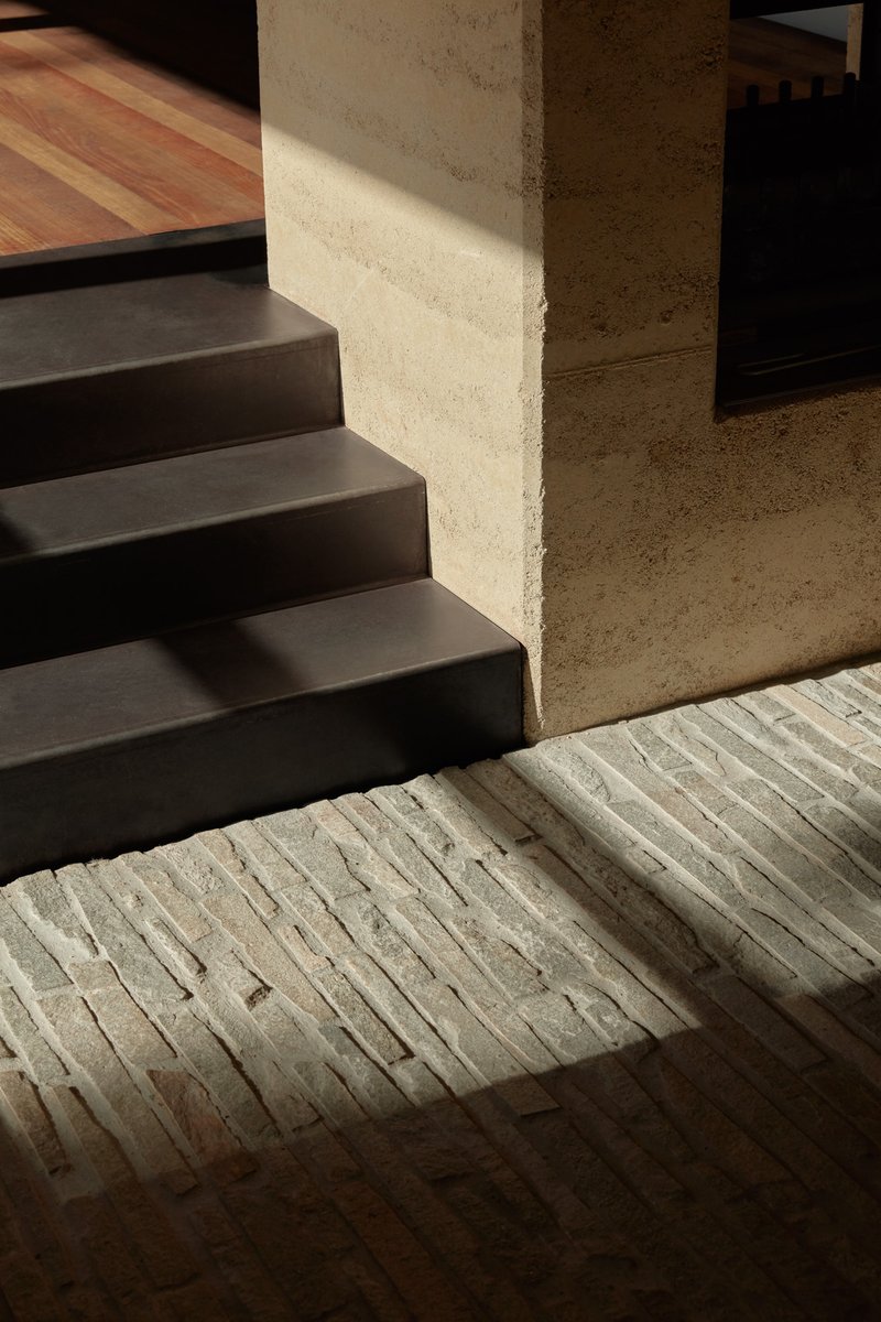 Steel stairs meeting ridged concrete paving where sunlight catches the textured surface