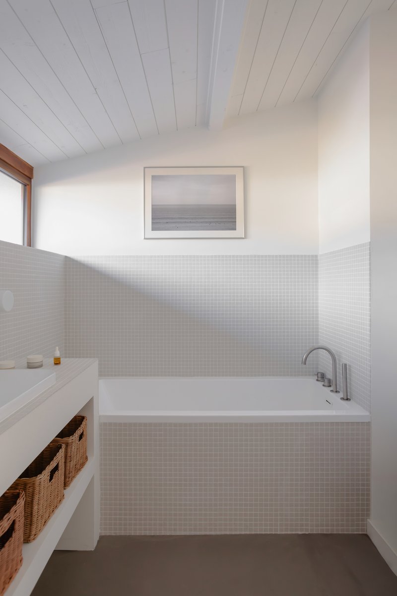 Bathroom with white mosaic tile surround, built-in tub and timber-trimmed window above