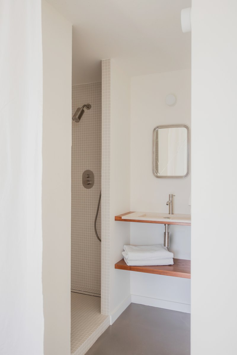 Bathroom view showing mosaic-tiled shower alcove and floating timber vanity with towels beneath