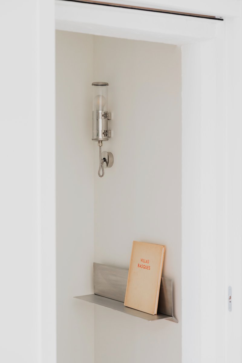 Built-in wall niche with glass sconce above and books on the ledge