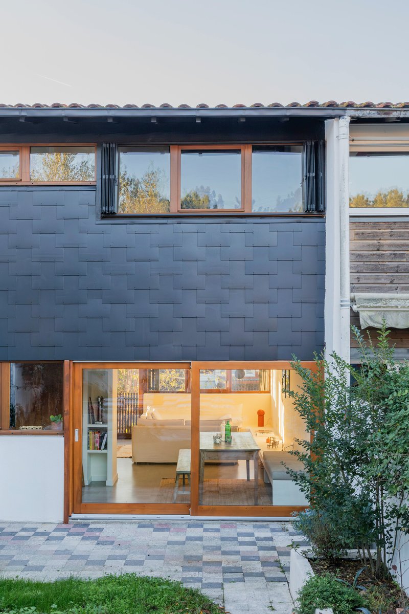 Rear elevation showing dark tile wall with sliding timber doors opening to a paved courtyard