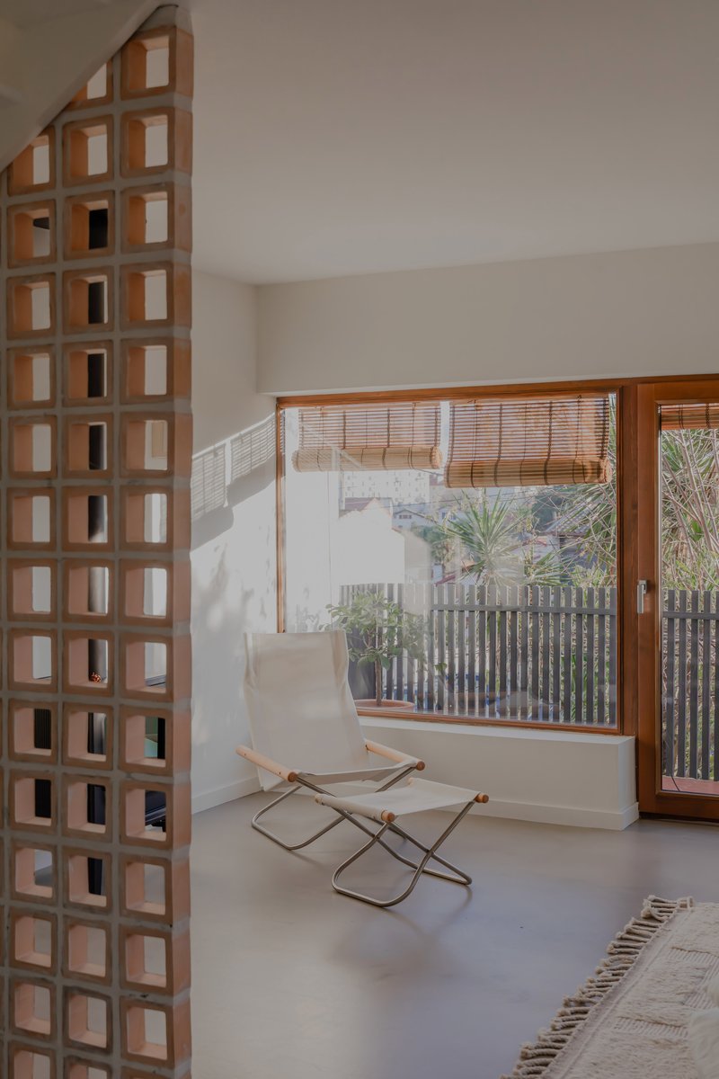 Timber grid partition wall beside window with rolled bamboo shade overlooking planted courtyard with vertical screening
