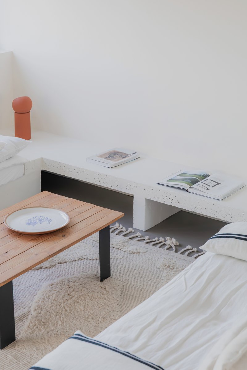 Concrete bench with built-in shelf above timber coffee table and low seating on a jute rug