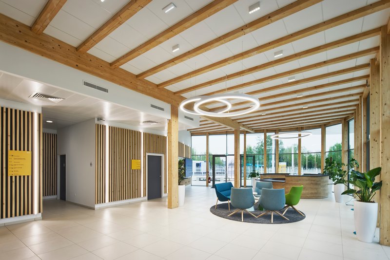 Reception area with timber ceiling grid and circular light fixtures suspended above tiled floor
