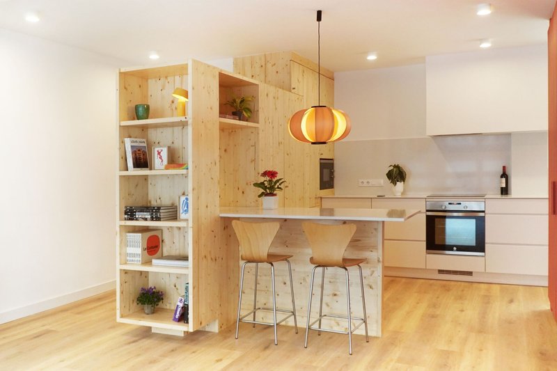 Timber breakfast bar with built-in shelves and warm pendant light above two stools