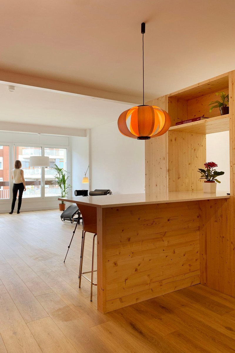 Kitchen island clad in knotted pine with an orange pendant lamp overhead