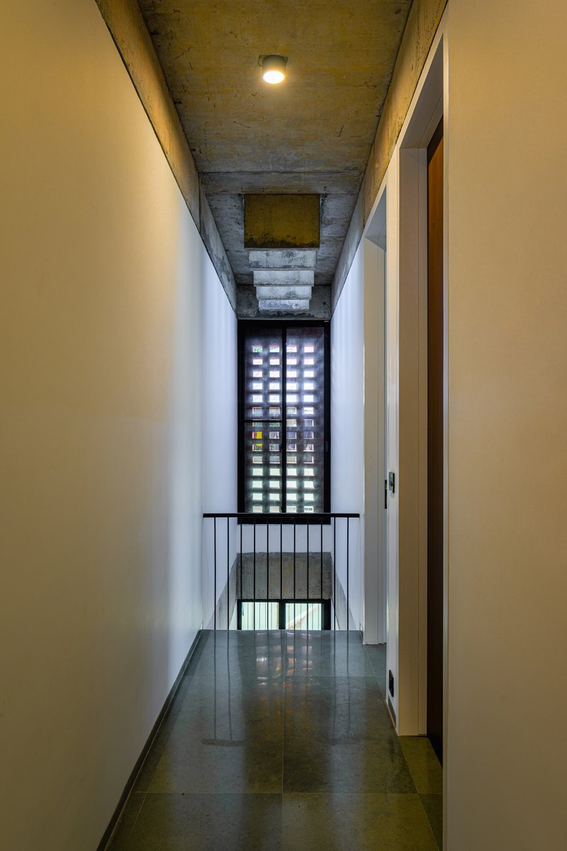 Narrow corridor with perforated screen wall at end and exposed concrete ceiling overhead