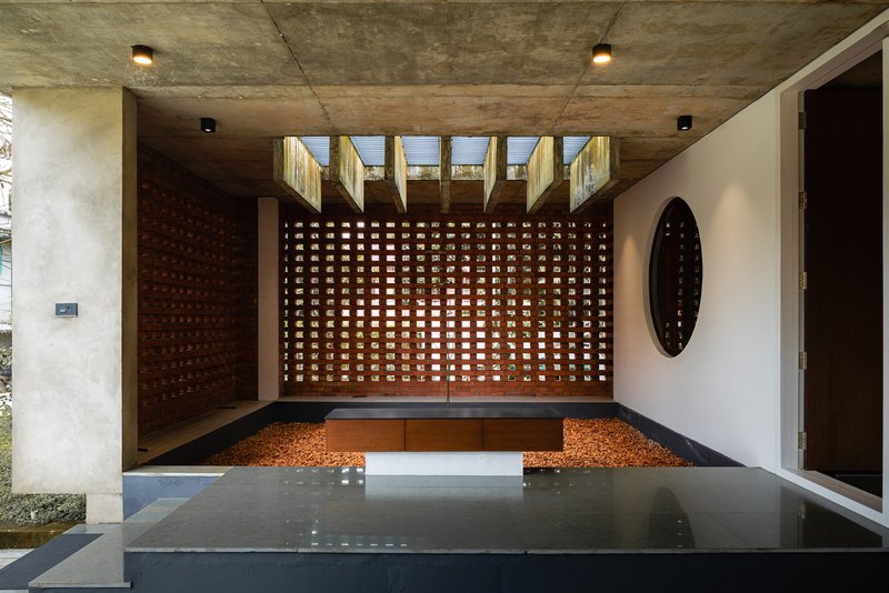Interior courtyard with perforated brick wall, reflecting pool, and exposed concrete ceiling with clerestory openings
