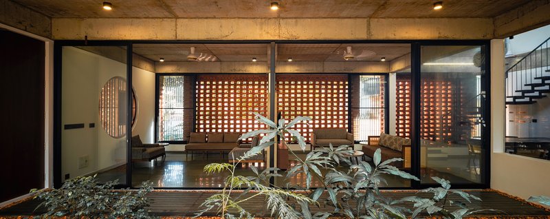View across the courtyard showing perforated brick screens and interior rooms with polished concrete floors