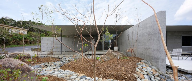 Courtyard with young trees planted in mulch and stone borders beneath the roof overhang