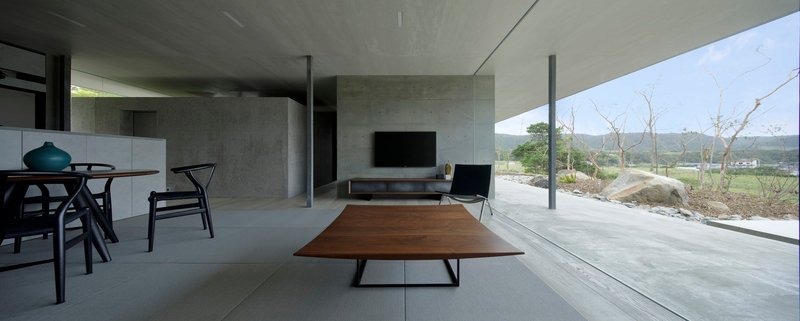 Interior view with walnut coffee table and glazed terrace overlooking low vegetation and distant hills