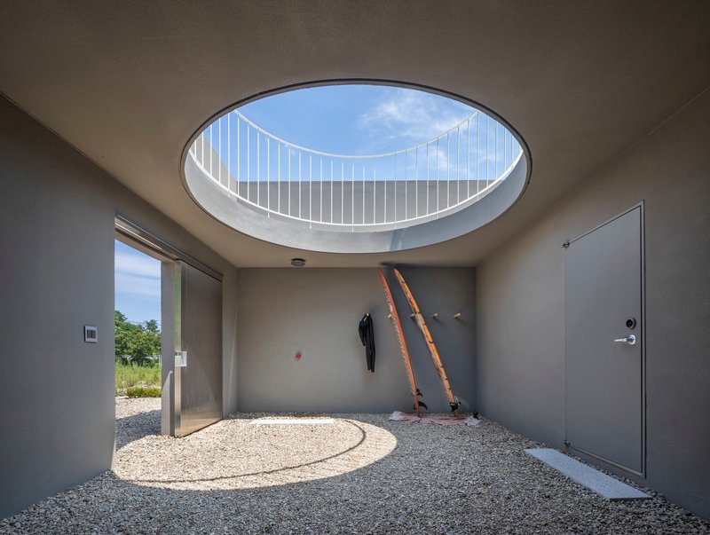 Interior courtyard with circular skylight framing white metal railing and wooden ladders against wall