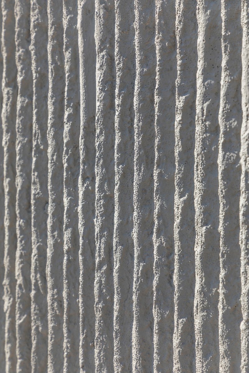 Close-up of vertical ribbed concrete surface showing textured formwork pattern in natural light