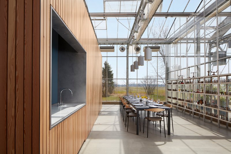 Dining area with long table set for a meal beneath the glazed roof with views to winter fields