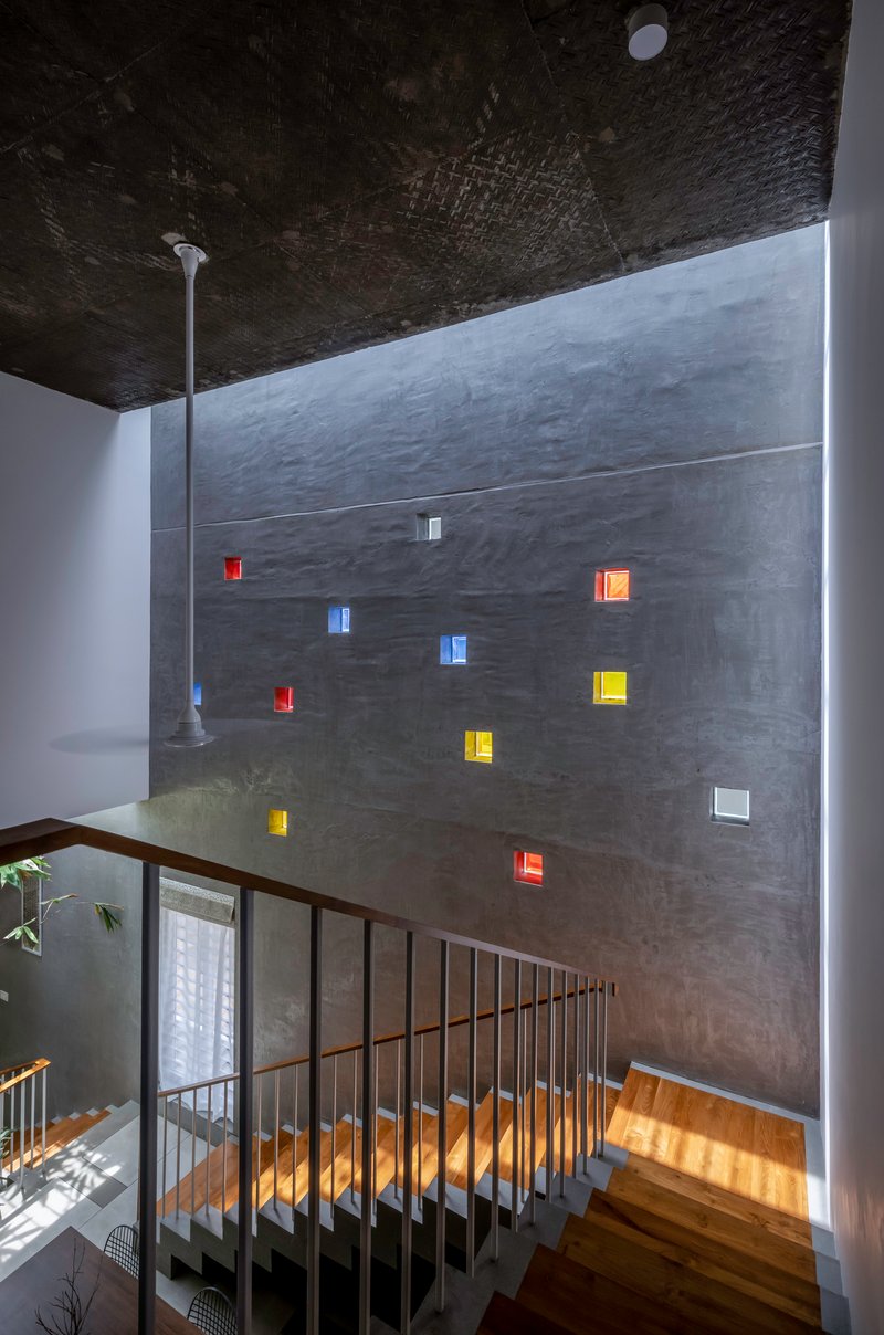 Tall concrete wall with scattered colored glass block inserts beside a metal-railed staircase