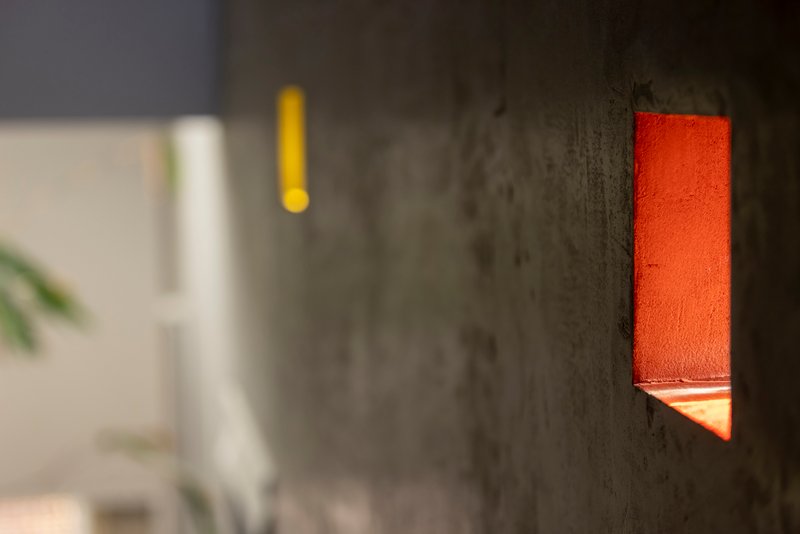 Close-up of an orange sconce set into a textured concrete wall