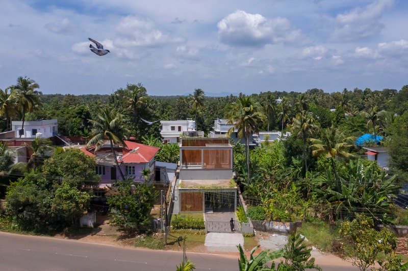 Aerial view of a residence with timber screens among palm trees and neighboring rooftops