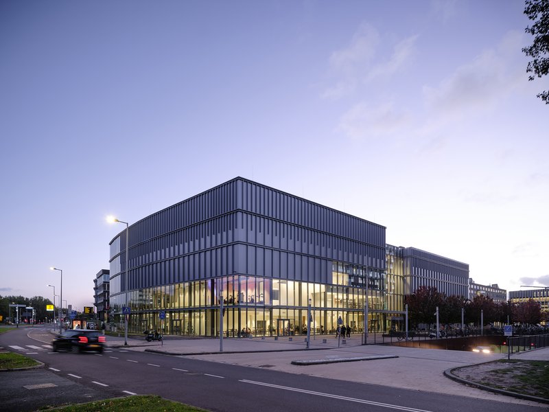 Corner view of the illuminated glass base and vertical metal facade at dusk