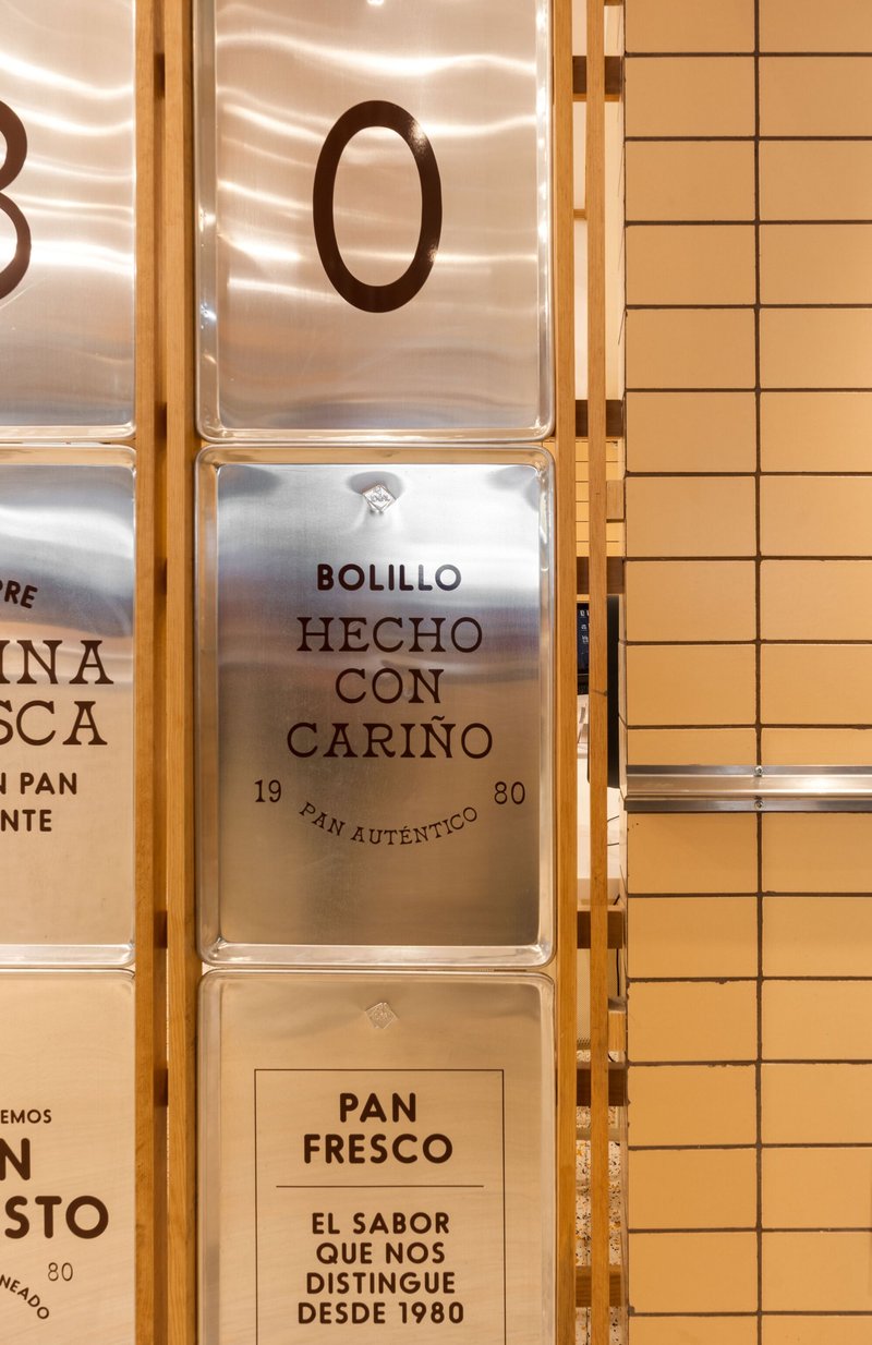 Close-up of translucent menu panels framed in timber against a cream tile wall
