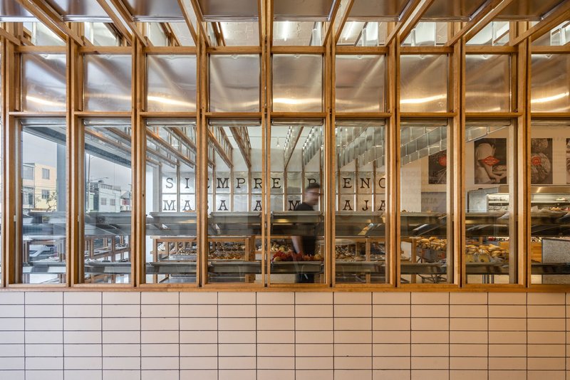 Street view through timber and glass storefront with white tile base and baked goods on display