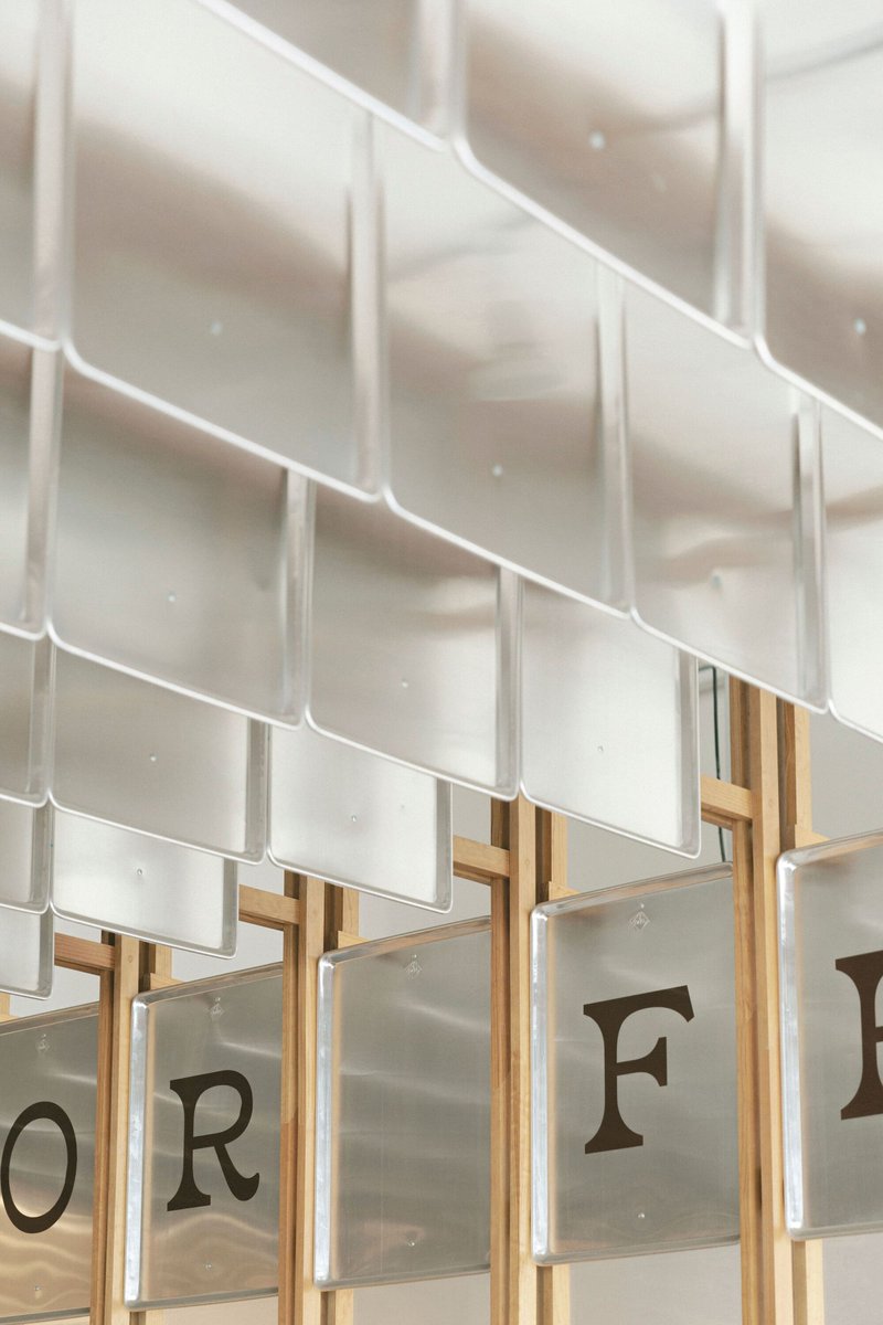 Detail of white ceramic tile shingles overlapping above timber framing and printed glass panels