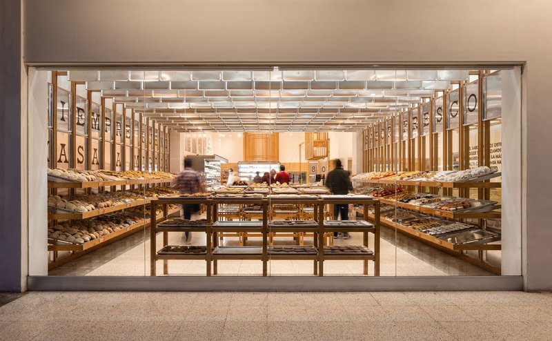 Street view through the glass storefront into the timber-framed bakery with customers browsing