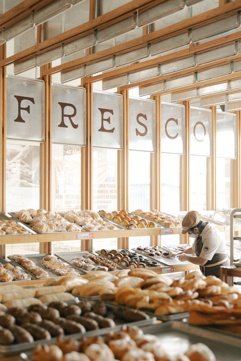 Angled view of the display tables loaded with pastries and a customer in afternoon light