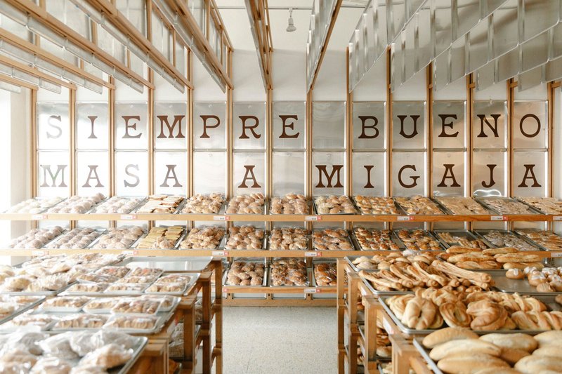 Wide view of the timber shelving system with hanging glass panels and trays of baked goods