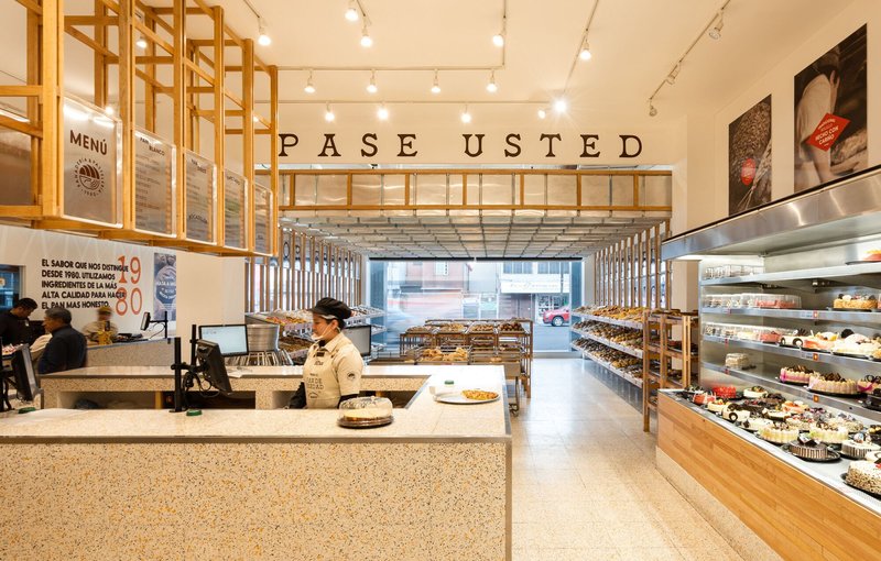 View through the service counter toward the timber pergola structure extending to the street window
