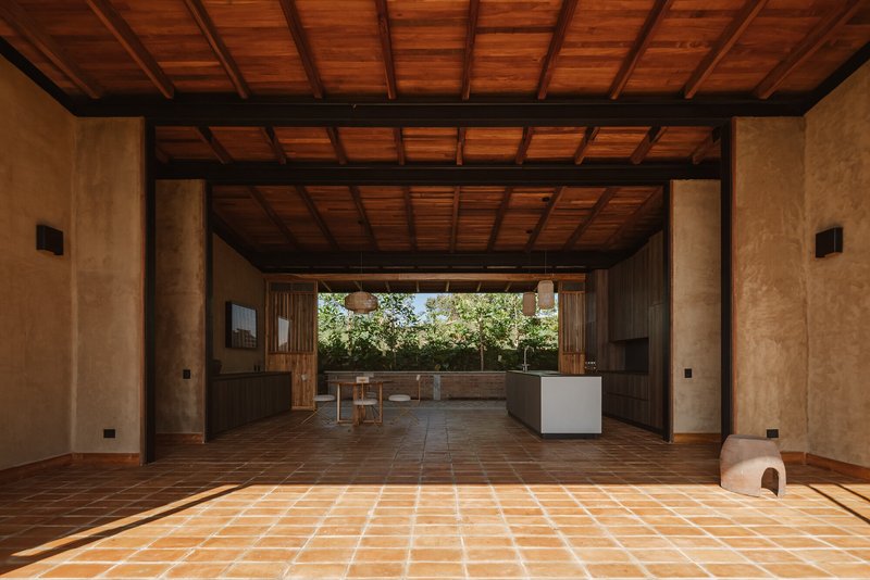 Interior living space with exposed beam ceiling and terracotta floor opening to outdoor terrace through sliding doors