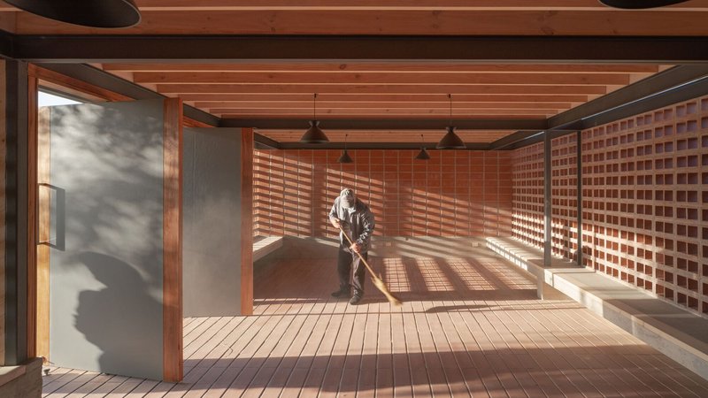 Interior space with sliding glass doors and perforated brick walls creating geometric shadow patterns