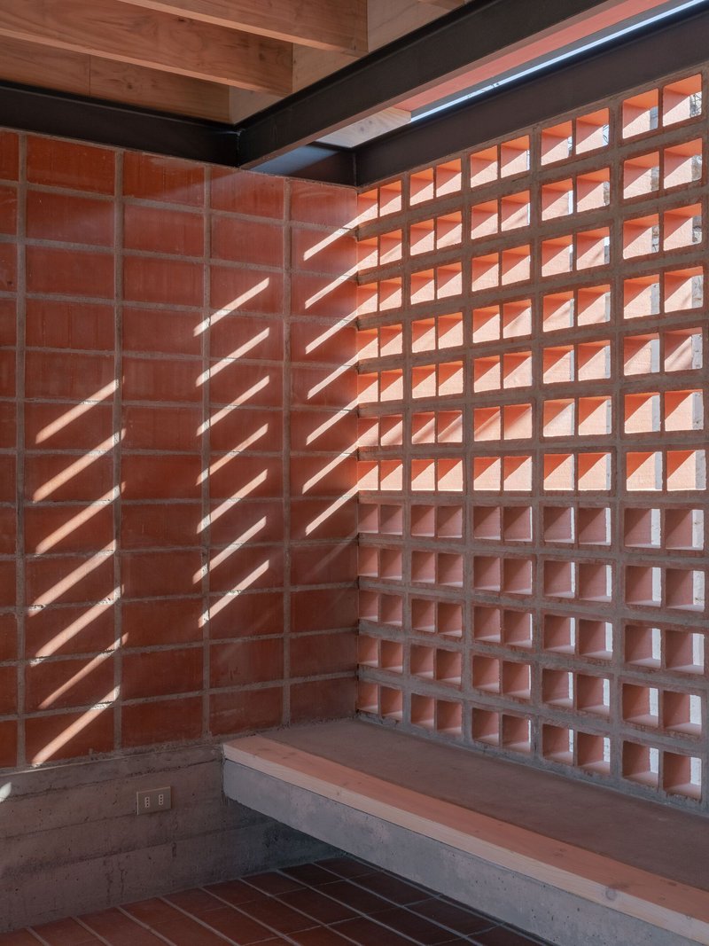 Interior corner with terracotta block walls and concrete bench casting diagonal shadows