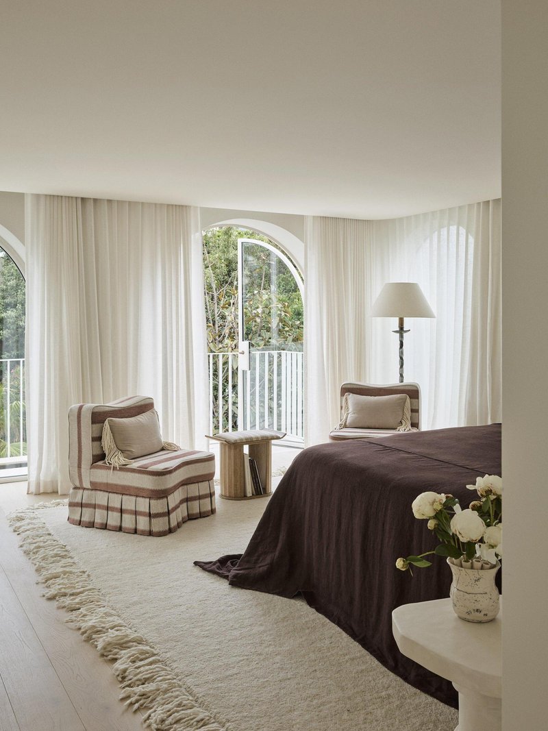 Bedroom with arched doorway opening to a balcony framed by flowing curtains