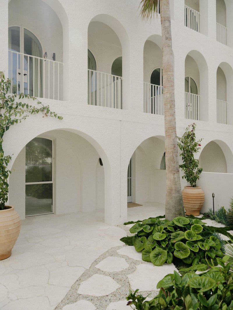 Interior courtyard with stone paving, palm trunk and terracotta planters under arcaded walkways